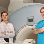 Radiologic technician smiling at mature female patient lying on