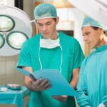 Two surgeons studying file in operating theatre in hospital