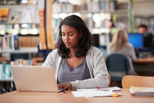 Nursing student studying at a desk in a library.