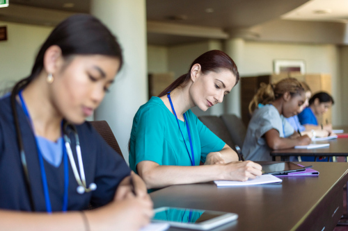 Nurses sitting at a long table and taking a test