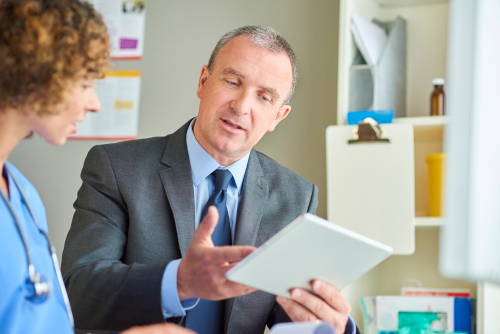 A nurse discussing information with a man in a suit