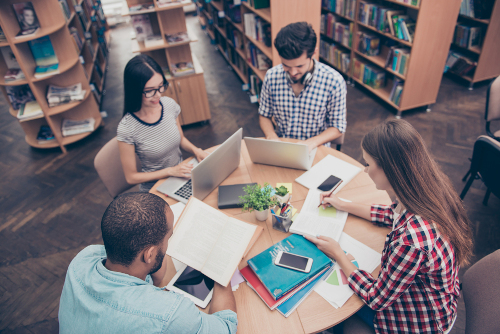 A group of students sitting around a table in a library and studying