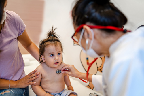 A pediatric nurse using a stethoscope on a baby