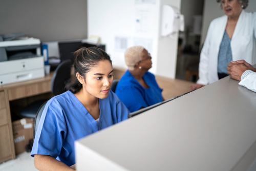 A medical assistant sitting at a desk working on a computer