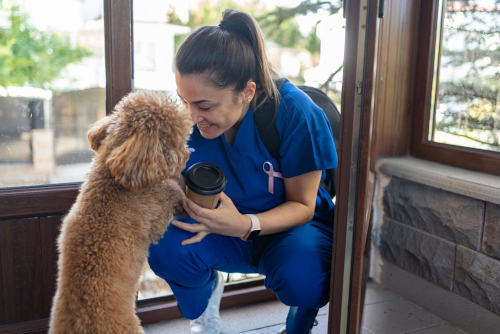 Nurse in scrubs coming home to her dog