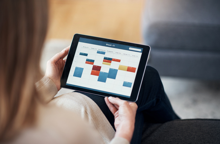 A woman using a scheduling tool on a tablet