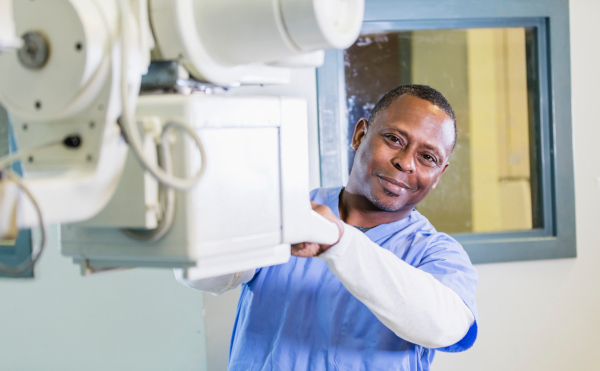 A radiological technologist hold on to part of an x-ray machine